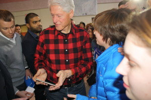 Former president Bill Clinton greets supporters at a Hillary for America rally at Milford Middle School in New Hampshire, while presidential candidate Hillary Clinton helps with the water crisis in Flint, Michigan. Photo by Sharon Lee