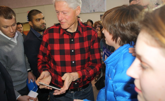 Former president Bill Clinton greets supporters at a Hillary for America rally at Milford Middle School in New Hampshire, while presidential candidate Hillary Clinton helps with the water crisis in Flint, Michigan. Photo by Sharon Lee